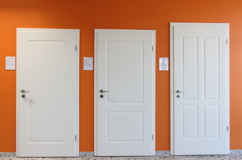 drei weiße Zimmertüren in einer orangenen Wand